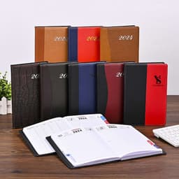 A range of PU leather diaries in various colours, including brown, red, black, and blue, displayed on a wooden table.