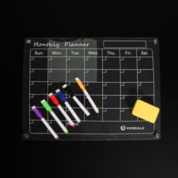 A magnetic dry erase calendar whiteboard set with a black surface, colourful markers, and an eraser. It features a branding logo.