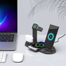 A black 4-in-1 wireless charging stand with compartments for a smartphone, AirPods, and a smartwatch on a desk.