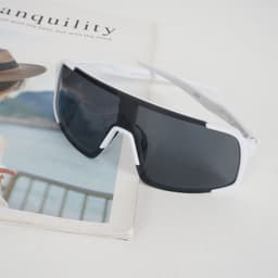Polarized UV protection sunglasses with a black and white frame, resting on a magazine.