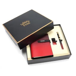 A red notebook, pen, and clip presented in a sleek black gift box with gold accents and a logo.