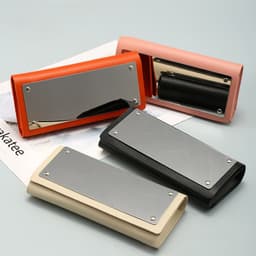 A selection of spectacle cases in orange, pink, black, and beige, each featuring a mirror on the front.