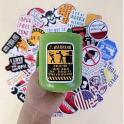 A green drink bottle held in hand, surrounded by a variety of stickers with different designs and colours.