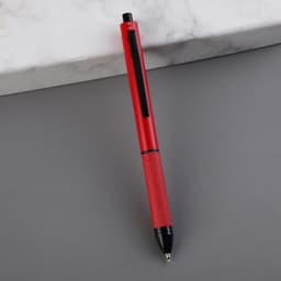 A red 4-in-1 ballpoint pen with a textured grip and a black clip, placed on a grey surface.