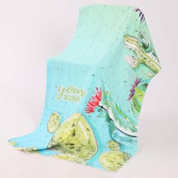 A soft, quick-drying beach towel in mint green with a cactus design and vibrant floral accents, featuring a logo.
