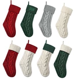 Eight large cable knitted Christmas stockings in red, green, grey, and cream, featuring textured knit patterns and looped tops.
