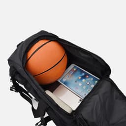A black duffel bag with zippered pockets, containing a basketball and a tablet.