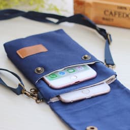 A navy canvas mobile phone shoulder bag with two smartphones inside, featuring a flap closure and an adjustable strap.
