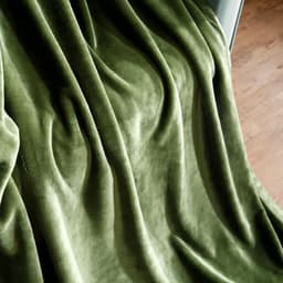 A soft, green flannel lap blanket draped elegantly, showcasing its smooth texture and plush appearance.