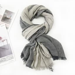 A soft shawl wrap scarf in grey and light grey, featuring tassels at the ends and arranged elegantly.