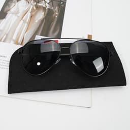 Polarised sunglasses with black lenses and a black felt storage bag, placed on a magazine.