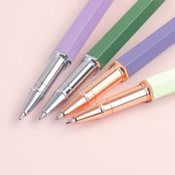 A collection of four personalised ballpoint pens in purple, green, and cream with silver and rose gold accents.