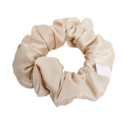 A custom satin scrunchie in a soft beige colour, featuring a simple design and a small tag.