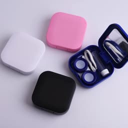 A portable contact lens case in pink, white, black, and blue, featuring a mirror and lens accessories inside.