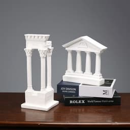 A pair of white resin 3D model ornaments resembling classical architecture, displayed on a stack of books.