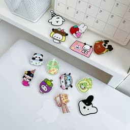 A collection of brightly coloured custom acrylic lapel pins featuring cute characters and designs on a flat surface.