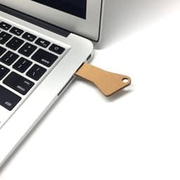 A biodegradable 4GB USB flash drive is connected to a laptop, featuring a brown, eco-friendly design.