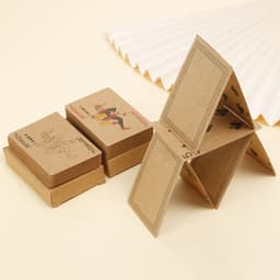 Kraft paper playing cards in brown packaging, featuring various designs, stacked and arranged in a house shape.