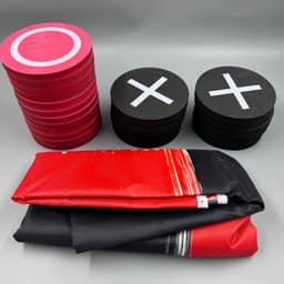 Red and black checkers with circles and crosses, alongside a folded game mat. The set is vibrant and playful.