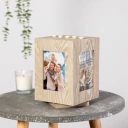 A wooden rotating cube photo frame featuring four picture openings, with a light wood finish.