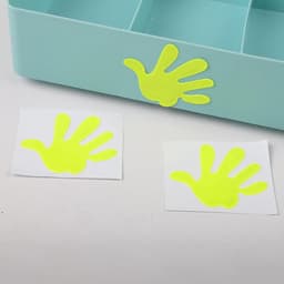 A close-up of reflective yellow high visibility stickers shaped like handprints on white backing.