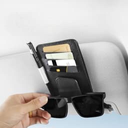 A black car sun visor card holder with slots for cards and a pen, shown with sunglasses being held below it.