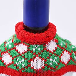 A drink bottle dressed in a festive red, green, and white knitted sweater with a patterned design.
