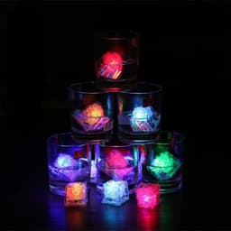 A stack of glasses contains colourful LED light-up ice cubes, glowing in red, blue, green, and yellow against a dark background.