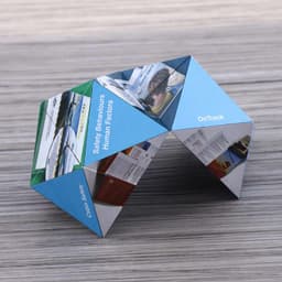 A fold-out magic cube in blue, featuring various images and texts on its triangular faces, set on a wooden surface.