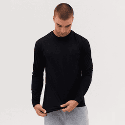 A long sleeve tee in black, worn by a model inspecting the hem, with a casual fit and long sleeves.
