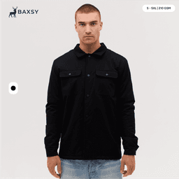 A man wearing a black Studio Canvas Jacket, featuring pockets and a collared design.