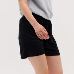Black Core Shorts featuring an elastic waistband, shown worn with a grey top.