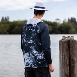 A men's polyester sublimated 1/4 zip fishing hoodie in navy and grey, featuring a hood and a logo, worn by a person by the water.