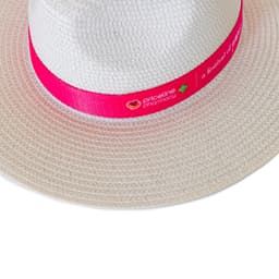 A white straw fedora hat with a bright pink band featuring a logo.