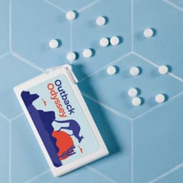 A rectangular white container of sugar-free breath mints with a colourful design, surrounded by white mints, on a blue background.