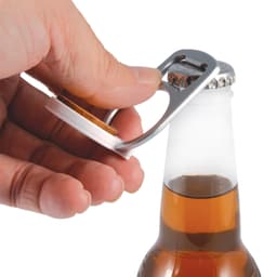 A drink bottle opener in silver, designed as a phone stand, being used to open a glass bottle.
