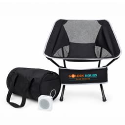 A portable black camping chair with a mesh back, accompanied by a black storage bag and a small speaker.