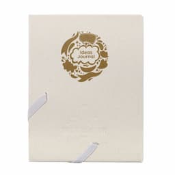 A cream-coloured journal with a decorative gold design and an elastic band closure. It features a logo on the cover.