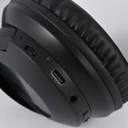 A close-up of black headphones featuring buttons and a USB-C port. There is a logo on the side.