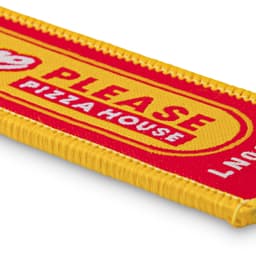 A woven keytag in red and yellow with a branded logo and text design.