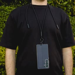 A phone lanyard in black, securely holding a smartphone around a person's neck against a green background.