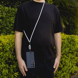 A phone lanyard in white attached to a black smartphone, worn around the neck of a person in a black shirt.