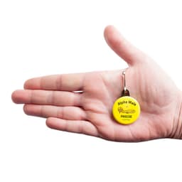 A hand holding a yellow 32mm round zipper pull with a metal clip and a logo.