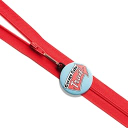 A red zipper pull featuring a custom printed light blue round button with a logo.