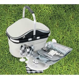 A grey and black picnic carry bag with cutlery, plates, glasses, and salt and pepper shakers on grass.