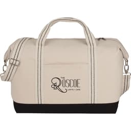 A cotton canvas duffel bag in cream with black accents, featuring handles and a detachable shoulder strap.