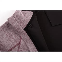 A close-up of a maroon and black zip hoodie featuring a textured fabric and an inner lining. It has a logo.