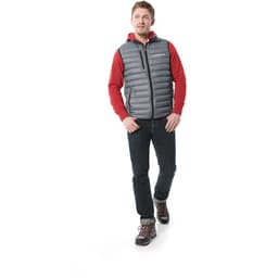 A man walks in a grey down vest over a red hoodie, paired with dark jeans and hiking boots. The vest has a logo.
