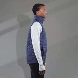 A navy puffer vest with a high collar, worn over a long-sleeve white top, featuring a logo on the chest.