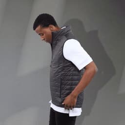 A men's lightweight packable insulated puffer vest in black, worn over a white shirt, featuring a logo.